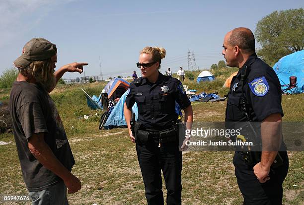 Sacramento police officers Sara Butler and Mike Cooper talk with a homeless man as they hand out eviction notices to residents at a homeless tent...