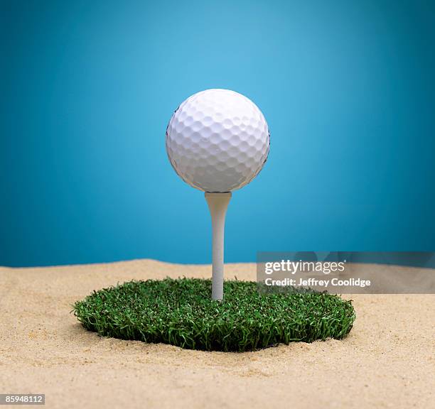 golf ball on tee surrounded by sand trap - golf bunker stock-fotos und bilder