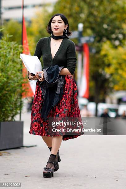 Guest wears a black cardigan, large flower print skirt, black fishnet socks and black wedge shoes , outside Ann Demeulemeester, during Paris Fashion...