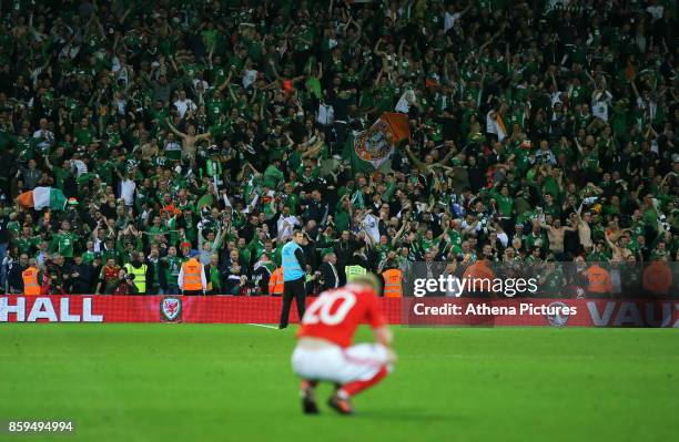 Jonathan Williams of Wales sits on the ground dejected while Ireland players celebrate their win in the background during the FIFA World Cup...