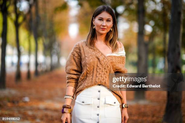 Angelica Ardasheva wears a camel V-neck pullover and a white skirt, outside the Rochas show, during Paris Fashion Week Womenswear Spring/Summer 2018,...