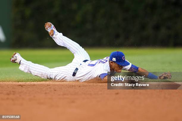 Addison Russell of the Chicago Cubs dives to field a ground ball in the seventh inning against the Washington Nationals during game three of the...