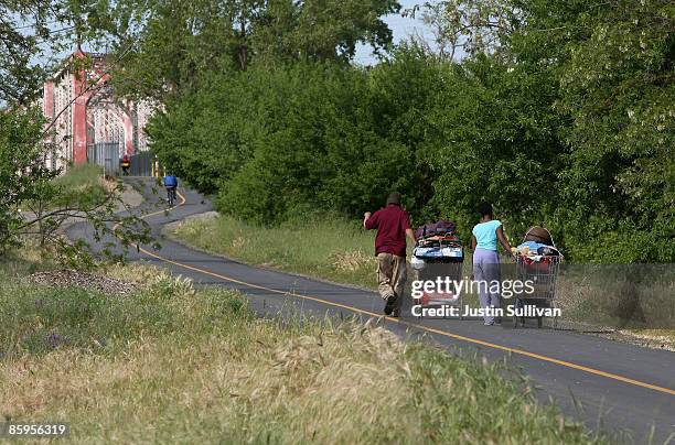 Homeless people pull shopping carts with their belongings as they leave a homeless tent city April 13, 2009 in Sacramento, California. Hundreds of...