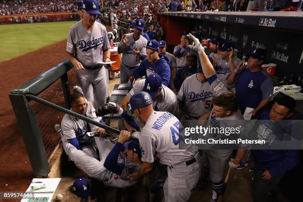 Cody Bellinger of the Los Angeles Dodgers falls into the dugout over manager Dave Roberts and third base coach Chris Woodward after catching a foul...
