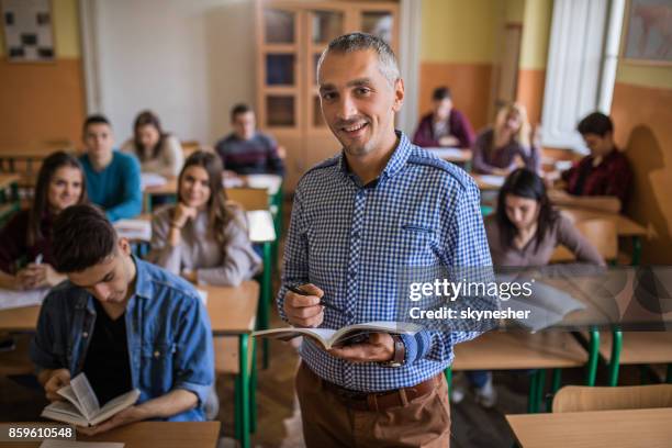 happy high school teacher looking at camera during the class in the classroom. - secondary school building stock pictures, royalty-free photos & images