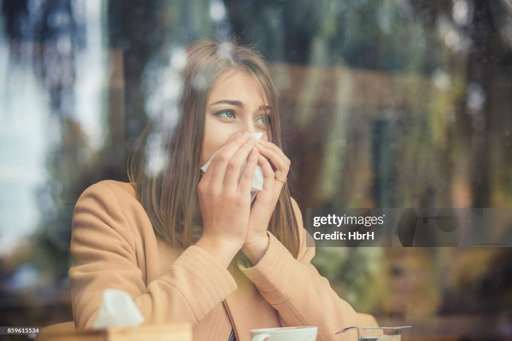 Jovem mulher tem alergia do nariz, espirros nasal gripe