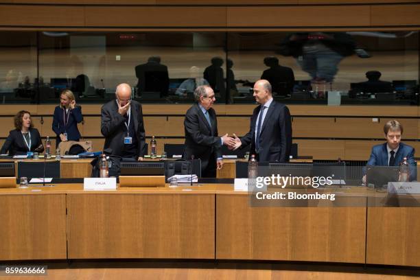 Pier Carlo Padoan, Italy's finance minister, center, shakes hands with Pierre Moscovici, economic commissioner for the European Union , ahead of an...