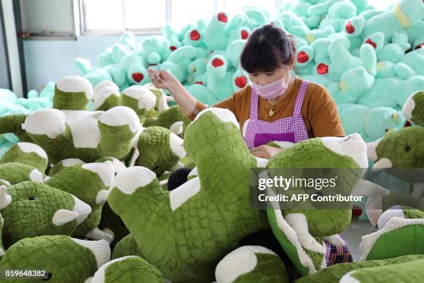 This photo taken on October 9, 2017 shows a Chinese employee making stuffed dinosaur toys as they are prepared to export for the upcoming Christmas...