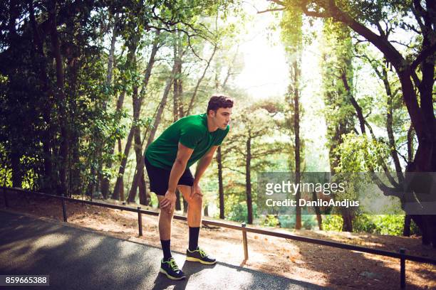 young man exercising in nature - hand on knee stock pictures, royalty-free photos & images