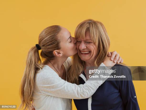 adult daughter hugging a elderly mother - studio kiss stock-fotos und bilder