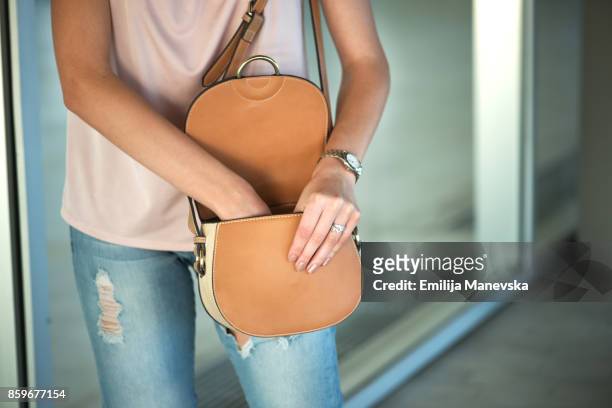 young woman searching in her purse - handtasche stock-fotos und bilder