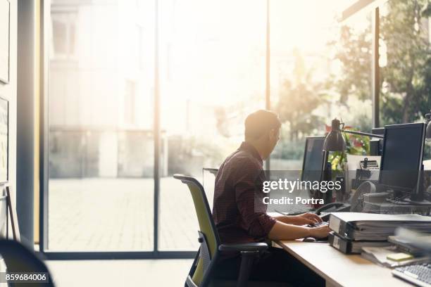 businessman working on computer at desk in office - sunny office stock pictures, royalty-free photos & images