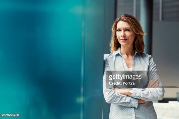 businesswoman with arms crossed at office - leaning stock pictures, royalty-free photos & images