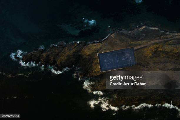 aerial picture taking with drone of a stunning empty basketball court in the middle of an island surrounded by water and rocky terrain in visual and aesthetic picture taken from directly above view. - aerial view of football field imagens e fotografias de stock