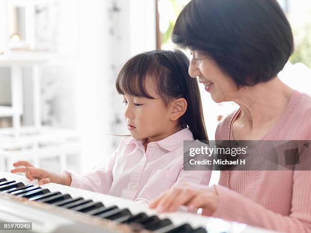girl who practices piano with grandma - fabolous musician stockfoto's en -beelden