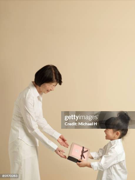 the girl passes the present to the grandma.  - child giving gift ストックフォトと画像