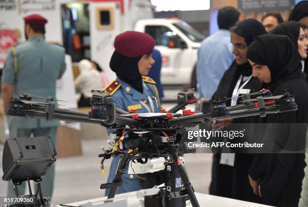 Policewoman stands next to a police drone at the Gitex 2017 technology exhibition at the Dubai World Trade Center in Dubai on October 10, 2017. / AFP...