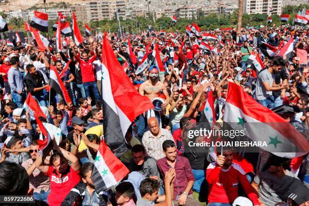 Syrians wave their national flag and cheer on their national team at the Umayyad Square in Damascus as they watch a broadcast of the World Cup...