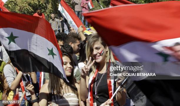 Syrians wave their national flag and cheer on their national team at the Umayyad Square in Damascus as they watch a broadcast of the World Cup...