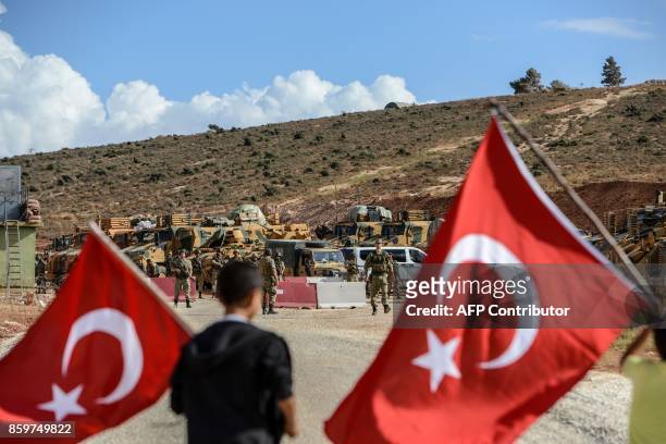Turkish soldiers stand near armoured vehicles as two young boys waving Turkish national flags arrive during a demonstration in support of the Turkish...