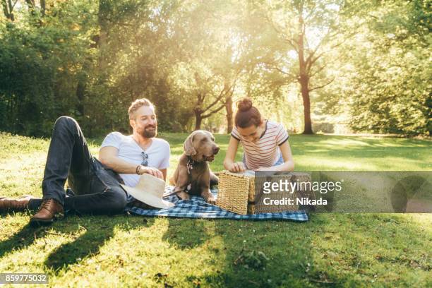 schuss von glücklicher vater mit tochter im teenageralter und hund liegend auf einer decke in einem park - family dog stock-fotos und bilder