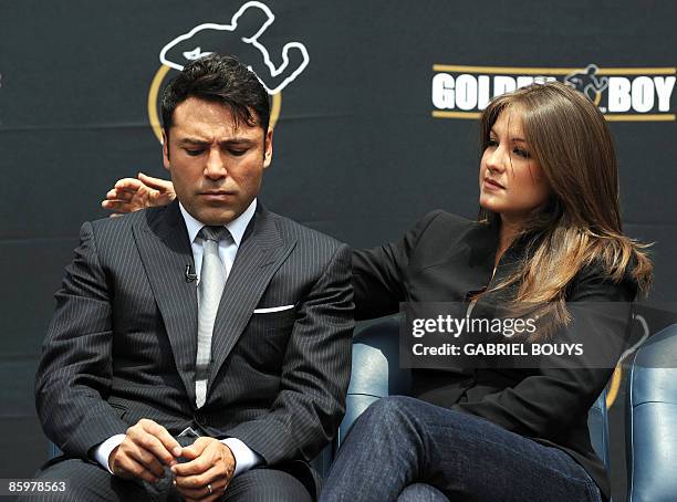 Oscar De La Hoya's wife Millie Corretjer consoles him after he announced his retirement from boxing during a press conference in Los Angeles on April...