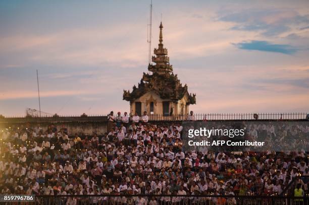 People hold candles and pray during the Interreligious Gathering of Prayer for Peace ceremony in Yangon on October 10, 2017. Tens of thousands of...