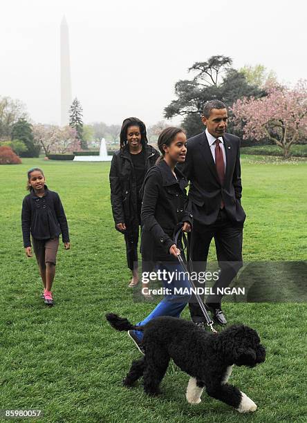 President Barack Obama , First Lady Michelle Obama and their daughters Malia and Sasha walk with the new family dog Bo, a Portuguese water dog, on...