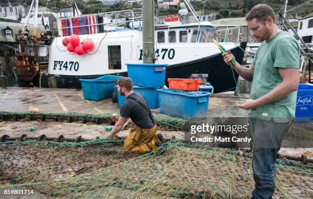 Fishermen mend their fishing nets besides the harbour in the village of Mevagissey which has submitted plans to limit the number of second homes on...