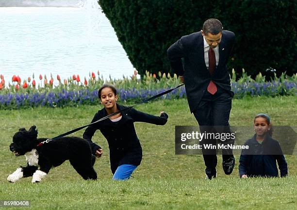 President Barack Obama with his daughters Malia and Sasha walk the family's new Portuguese water dog Bo, during the dog's introduction to the White...