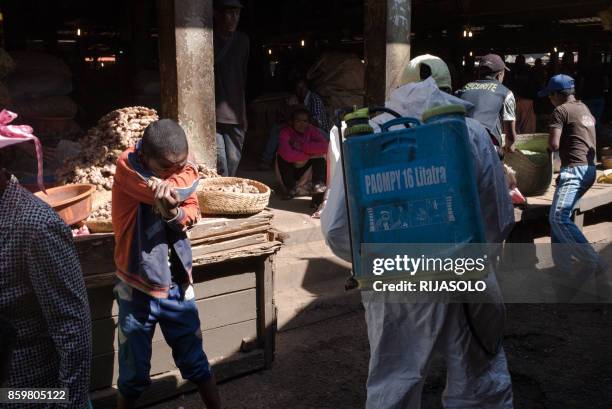 Boy covers his mouth as a council worker sprays disinfectant during the clean-up of the market of Anosibe in the Anosibe district, one of the most...