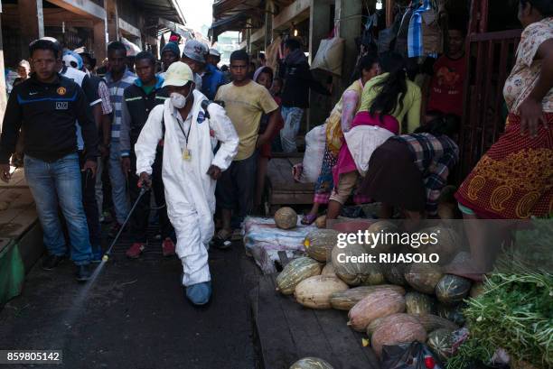 People stand back as a council worker sprays disinfectant during the clean-up of the market of Anosibe in the Anosibe district, one of the most...