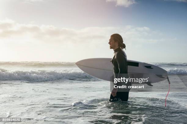 surfer vadea en el mar, la playa de fistral newquay, cornwall. - newquay fotografías e imágenes de stock