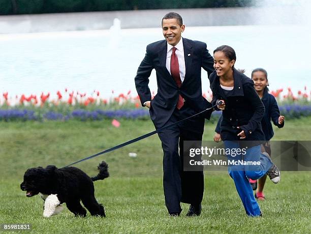 President Barack Obama with his daughters Malia and Sasha walk the family's new Portuguese water dog Bo, during the dog's introduction to the White...