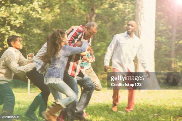 multi-ethnic family playing football in backyard at thanksgiving. - thanksgiving day stock pictures, royalty-free photos & images