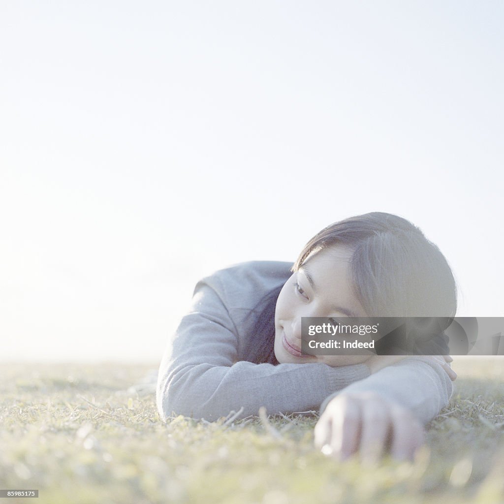 Young woman lying on grass, looking away