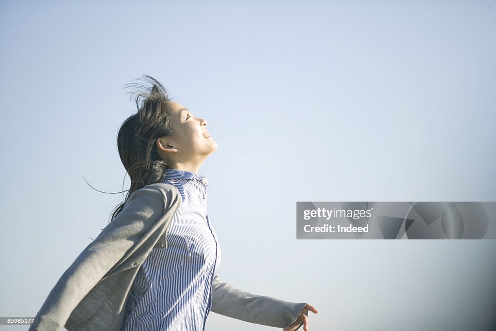 Young woman running and looking at sky, side view