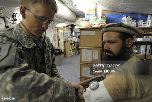 Army medic treats an Afghan patient at a medical centre of ISAF's Camp Bostick in Naray, in the eastern Kunar province on April 15, 2009. Afghanistan...