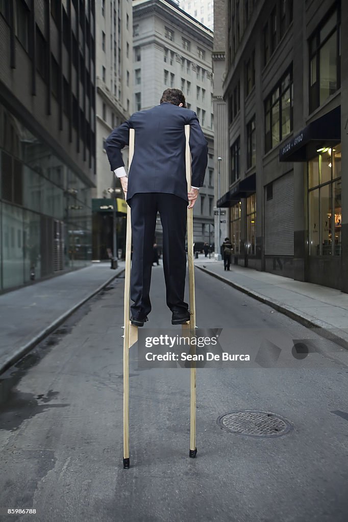 Businessman balancing on stilts