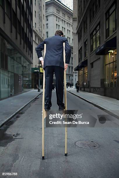 businessman balancing on stilts - stilt stock pictures, royalty-free photos & images