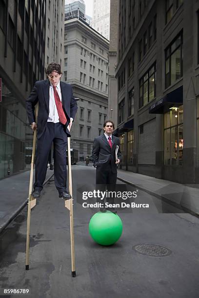 businessmen balancing on stilts and exercise ball - stelze stock-fotos und bilder