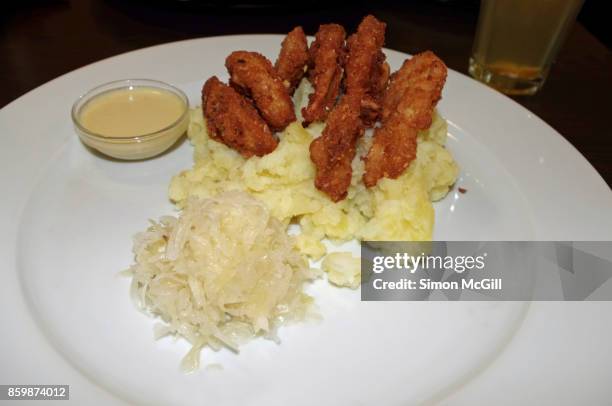 chopped up schnitzel in coarsely mashed potato with a side of sauerkraut and a dipping sauce - prague food photos et images de collection