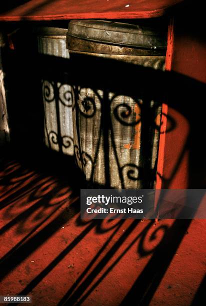 The shadow of a railing on a row of dustbins, circa 1975.