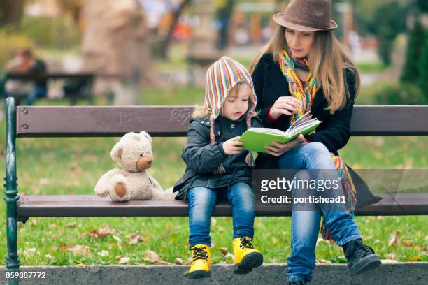 madre e figlio che leggono un libro nel parco - 2 3 anni foto e immagini stock