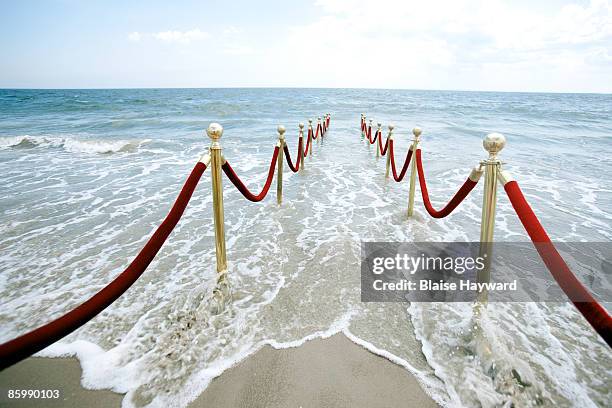 red velvet ropes leading to ocean - red carpet barriers stock pictures, royalty-free photos & images