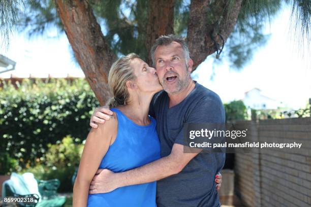 mature blond lady kissing her husband - friends kissing cheeks fotografías e imágenes de stock