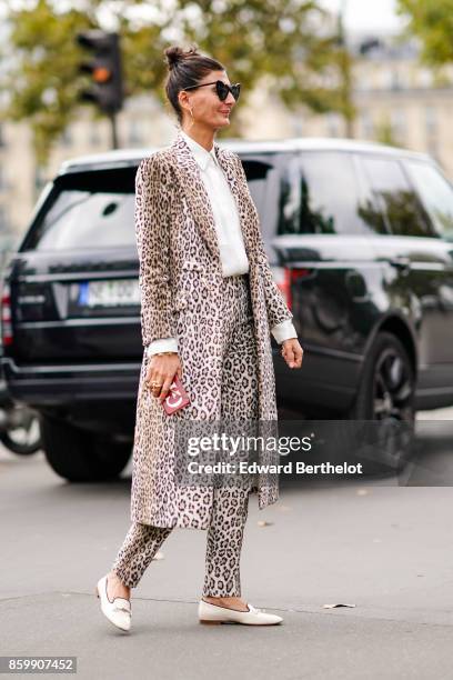 Giovanna Battaglia wears sunglasses, a white shirt, a leopard print coat, leopard print pants, white moccasins, outside the Dries Van Noten show,...