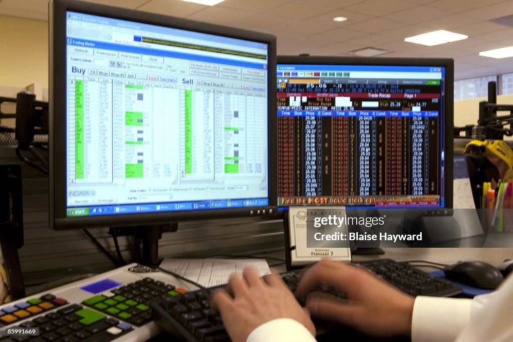 Hands typing at stock brokers desk