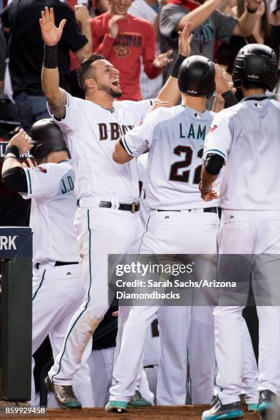 Jake Lamb of the Arizona Diamondbacks is congratulated by David Peralta after scoring during the National League Wild Card Game against the Colorado...