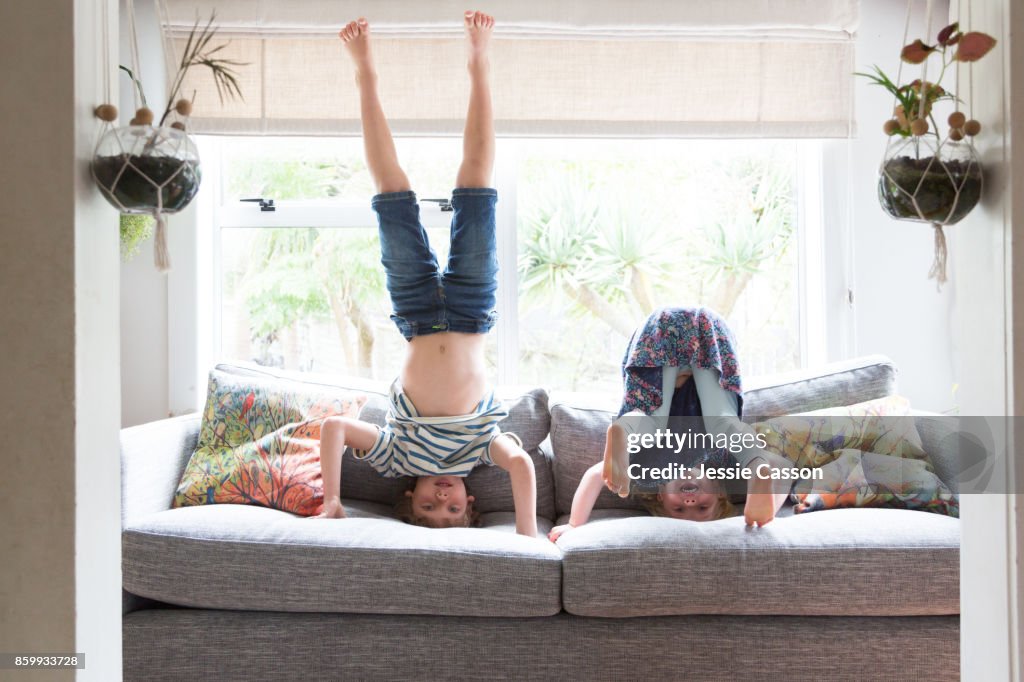 Siblings playing on sofa doing headstands